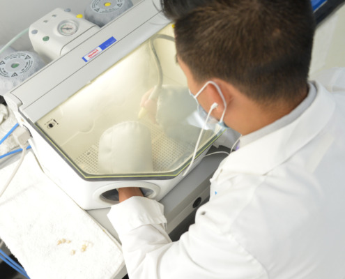 A man in a lab coat diligently operates a machine while working on a dental prosthetic in a high quality dental lab setting.
