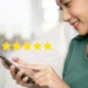A woman holding a smartphone with five stars, indicating a high rating or review of the business she is researching.