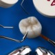 Dental crown preparation with different dental instruments and composites on a blue background.